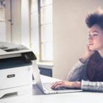 Jonge vrouw die op haar computer werkt naast een Xerox® B315 multifunctionele printer.