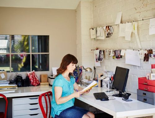 Telewerkende vrouw voor haar notebook en computer naast een Xerox C315 multifunctionele printer